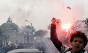 An Egyptian student holds a flare during a march from Cairo University to parliament headquarters as they condemn the military and demand the transfer of power during celebrations of National Student Day in Cairo